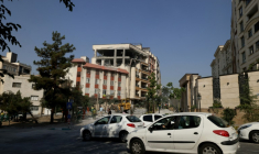 Des automobilistes passent devant un bâtiment endommagé après qu’il a été visé par une frappe israélienne dans la capitale iranienne, Téhéran, le 13 juin 2025 ( AFP / ATTA KENARE )