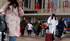 Des voyageurs marchent avec leurs bagages à l'extérieur de la gare de Pékin pendant la Fête du Printemps