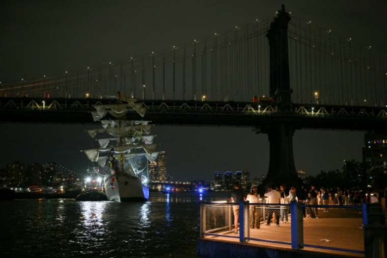 Des personnes regardent un navire-école de la marine mexicaine être tiré après avoir heurté le pont de Brooklyn à New York, le 17 mai 2025 ( AFP / ANGELA WEISS )