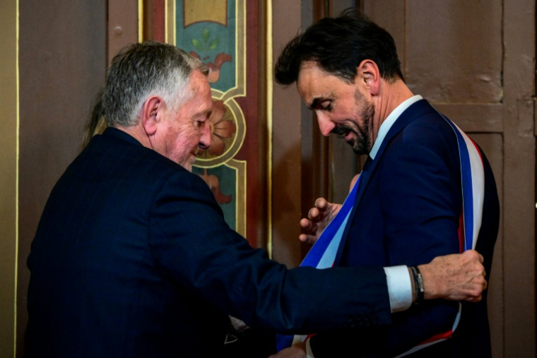 Le maire réélu Grégory Doucet, à droite, reçoit son écharpe des mains de Jean-Michel Aulas, à gauche, le 27 mars 2026, à Lyon ( AFP / OLIVIER CHASSIGNOLE )