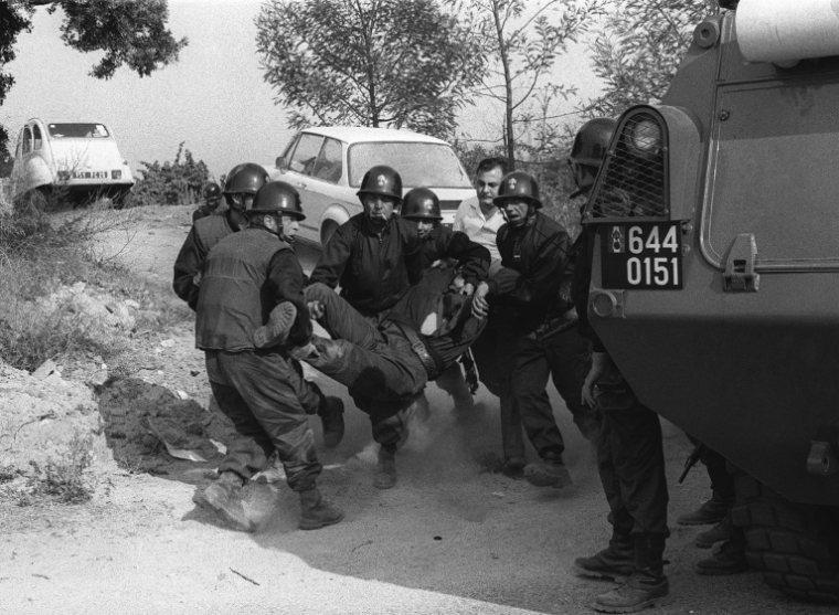 Des gendarmes évacuent un collègue blessé lors de leur intervention pour libérer six hommes pris en otage par des indépendantistes corses masqués et armés dans la cave à vin « Sovicor » à Aléria, en Corse, le 22 août 1975 ( AFP / STF )