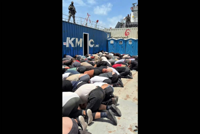 Image tirée d'une vidéo diffusée le 20 mai 2026 sur le compte X du ministre israélien de la Sécurité nationale, Itamar Ben Gvir, montrant des militants détenus, membres de la "Flottille pour Gaza", agenouillés, les mains liées dans le dos et le front au sol, sur le pont d'un bateau militaire en Israël ( Compte X du ministre israélien de la Sécurité nationale,Itamar Ben Gvir / - )