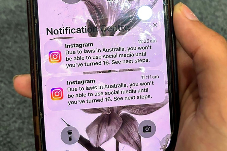 Un adolescent tient un téléphone portable affichant un message du réseau social Instagram après que son compte a été verrouillé en raison de son âge, à Sydney, le 9 décembre 2025 ( AFP / STR )