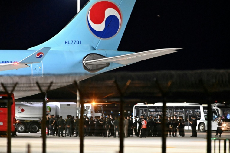 Des policiers cambodgiens et sud-coréens près de l'avion affrété pour rapatrier la soixantaine de Sud-Coréens soupçonnés d'implication dans des arnaques en ligne au Cambodge, à l'aéroport international de Techo, le 17 octobre 2025 ( AFP / TANG CHHIN Sothy )