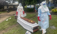 Des membres du personnel médical, en combinaisons de protection, près du cercueil d'un patient décédé du virus Ebola dans un hôpital à Rwampara, le 21 mai 2026 en RDC ( AFP / Seros MUYISA )