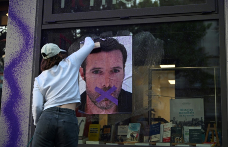 Une militante féministe colle une affiche dénonçant la publication d'un livre de Nicolas Bedos, condamné en octobre pour agressions sexuelles, à Paris, le 23 mai 2025 ( AFP / Leo VIGNAL )