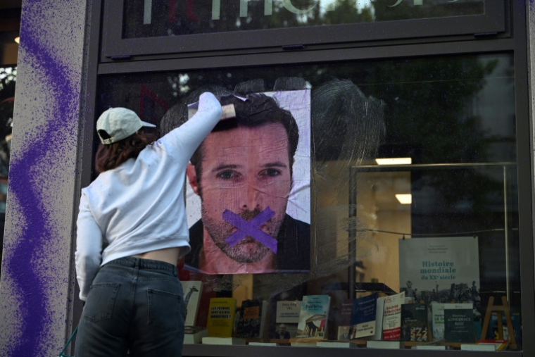 Une militante féministe colle une affiche dénonçant la publication d'un livre de Nicolas Bedos, condamné en octobre pour agressions sexuelles, le 23 mai 2025 à Paris ( AFP / Leo VIGNAL )