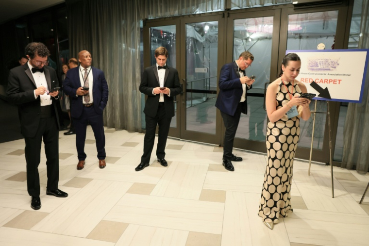 Des journalistes consultent leur portable après qu'un homme armé a tenté de forcer l'entrée du dîner des correspondants de la Maison Blanche auquel assistait le président américain Donald Trump, le 25 avril 2026 à Washington  ( AFP / Jemal COUNTESS )