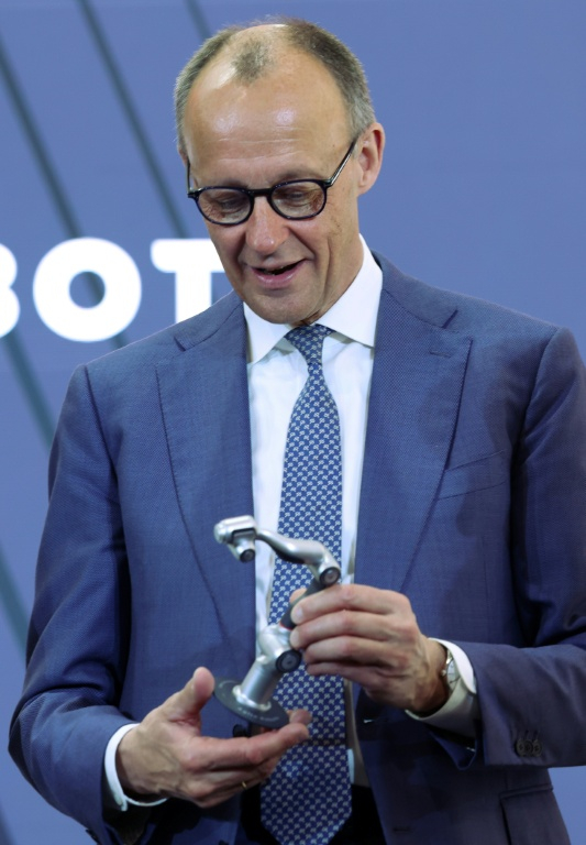 le chancelier allemand Friedrich Merz sur le stand d'Agile Robots à la foire industrielle d'Hanovre, 20 avril 2026 dans le nord de l'Allemagne ( AFP / Ronny HARTMANN )