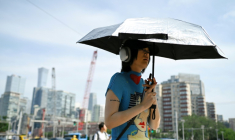 Une femme tient un parapluie pour se protéger du soleil, à Pékin, en Chine, le 23 juin 2025 ( AFP / WANG Zhao )