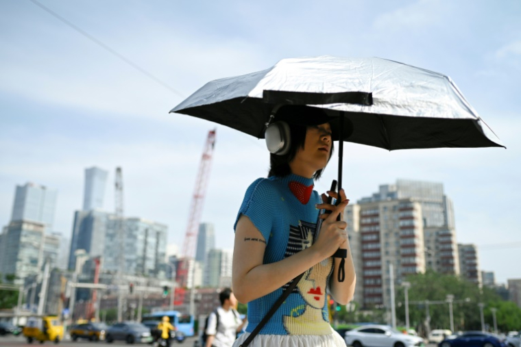 Une femme tient un parapluie pour se protéger du soleil, à Pékin, en Chine, le 23 juin 2025 ( AFP / WANG Zhao )