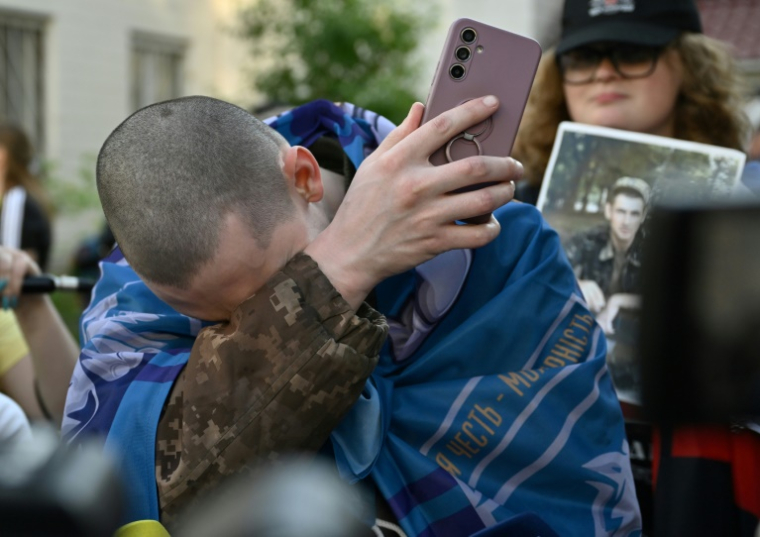 Un prisonnier ukrainien pleure après avoir parlé au téléphone avec ses proches à son arrivée après un échange de prisonniers dans la région de Tcherniguiv, le 23 mai 2025 ( AFP / Genya SAVILOV )