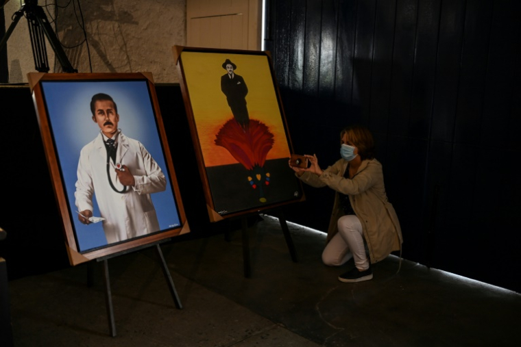 Une femme prend une photo de portraits du médecin vénézuélien Jose Gregorio Hernandez, installées dans la chapelle où a eu lieu sa béatification, à Caracas le 28 avril 2021 ( AFP / Yuri CORTEZ )