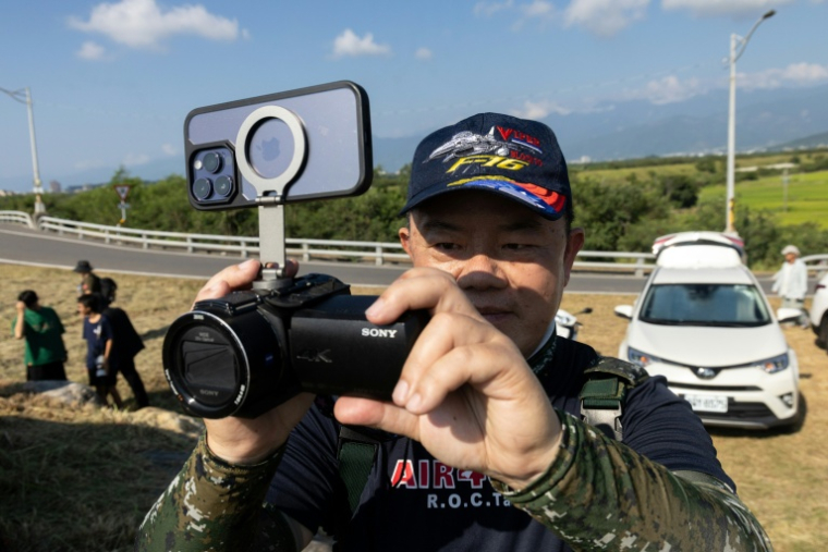 Un passionné d'aviation attend devant la base aérienne de Chihhang l'arrivée des nouveaux avions de chasse F-16V à Taitung, à Taïwan, le 2 octobre 2026 ( AFP / CHENG Yu-chen )