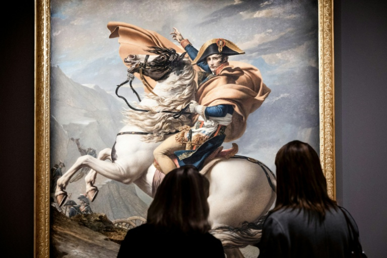 Des visiteuses devant le tableau "Bonaparte franchissant le Grand-Saint-Bernard" (1801) du peintre français Jacques-Louis David, le 14 octobre 2025 au musée du Louvre à Paris ( AFP / Alain JOCARD )