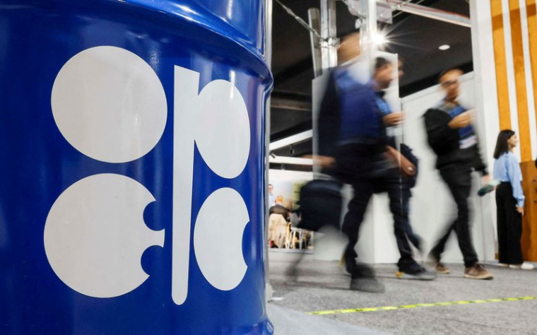 Des personnes passent devant un baril de pétrole avec le logo Opep lors de la COP29 à Bakou
