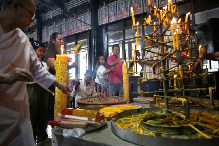 Des fidèles allument des bougies pour marquer le début du carême bouddhiste dans un temple de la province de Samut Sakhon, le 30 juillet 2026 (  / Lillian SUWANRUMPHA )