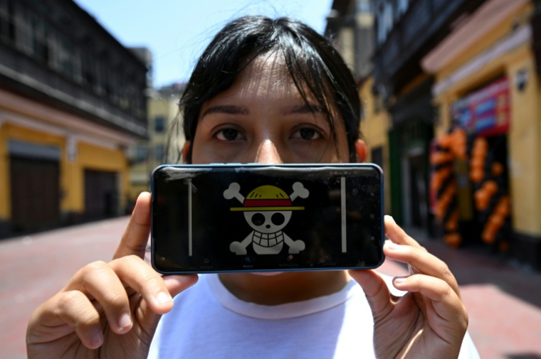 Rosalinda, diplômée en droit et membre du mouvement Gen Z, montre le drapeau du manga One Piece sur son téléphone portable lors d'une interview avec l'AFP à Lima, le 19 octobre 2025 au Pérou ( AFP / Raul ARBOLEDA )