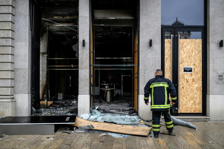 Un pompier devant les vitrines brisées d'un commerce, pillé et vandalisé, au lendemain d'une manifestation contre la vie chère à Lyon, le 18 octobre 2026 ( AFP / JEFF PACHOUD )