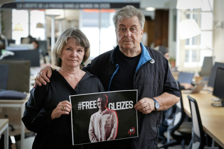 La mère du journaliste Christophe Gleizes, Sylvie Godard, et son beau-père Francis Godard posent avec une affiche demandant sa libération, le 27 août 2025 à Paris ( AFP / STEPHANE DE SAKUTIN )
