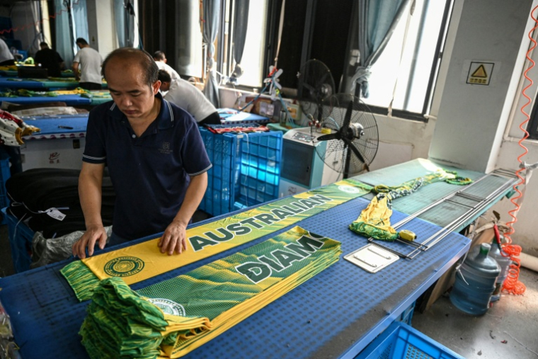 Un employé repasse des écharpes dans une usine qui produit des chapeaux et des écharpes à Yiwu, dans la province du Zhejiang, dans l'est de la Chine, le 18 septembre 2025 ( AFP / Jade GAO )