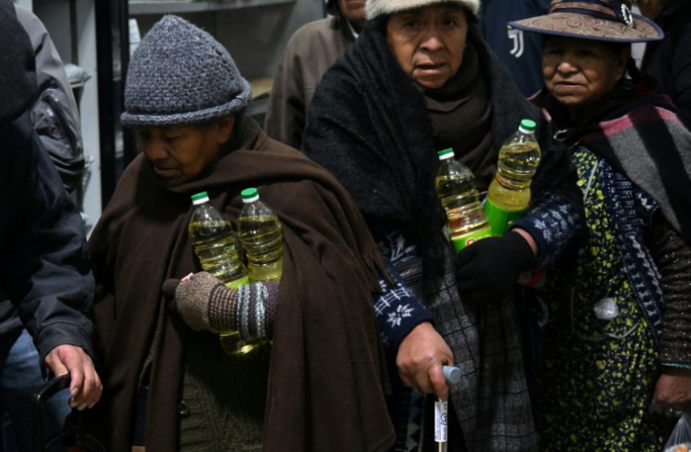 Des habitants repartent avec des bouteilles d'huile achetées dans un magasin Emapa à prix réduit, le 11 juin 2025 à La Paz, en Bolivie ( AFP / AIZAR RALDES )