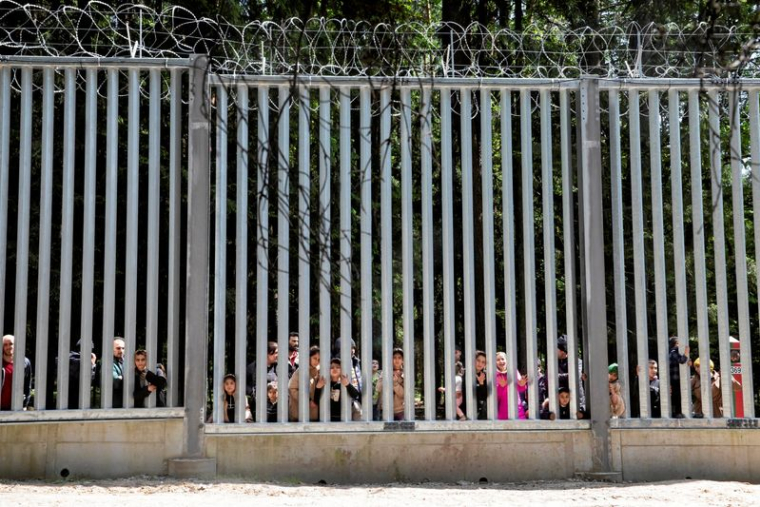Des migrants se tiennent près du mur à la frontière entre la Pologne et la Biélorussie, près de Białowieża