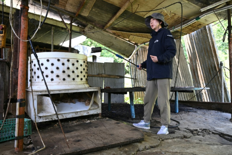 Un militant pour les droits des animaux montre un chalumeau à gaz à côté d'une machine à plumer dans un abattoir canin désaffecté à Pyeongtaek, le 11 juin 2026 en Corée du Sud ( AFP / Jung Yeon-je )