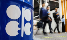 Des personnes passent devant un baril de pétrole avec le logo Opep lors de la COP29 à Bakou