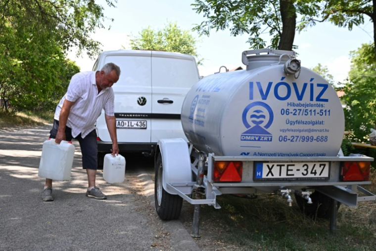 Istvan Bocsi, un habitant du village hongrois de Szada, va chercher de l'eau à un réservoir mobile, en pleine vague de chaleur, le 30 juin 2026 ( AFP / Attila KISBENEDEK )