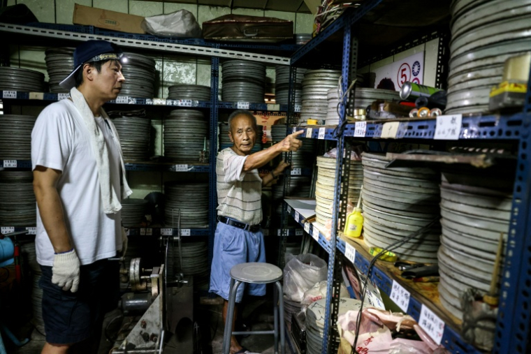 Le collectionneur Wang Chin-ting (D) montre des bobines de vieux films taïwanais à un membre de l'Institut taïwanais du cinéma et de l'audiovisuel (TFAI), le 29 mai 2026 à Changhua, dans la province de Taïwan ( AFP / I-Hwa Cheng )