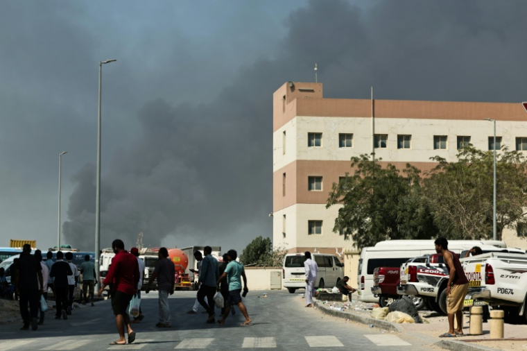Des gens regardent de la fumée s'élever du port de Jebel Ali après une frappe iranienne à Dubai, le 1er mars 2026  ( AFP / Fadel SENNA )