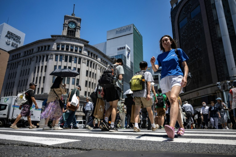 Des piétons dans une rue du quartier de Ginza à Tokyo où les températures ont dépassé les 34°C, le 18 juin 2025 ( AFP / Philip FONG )