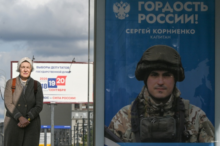 Une passante près d'une affiche faisant la promotion de l'armée russe en Ukraine sur laquelle on peut lire "Fierté de la Russie", à Moscou le 15 septembre 2026 ( AFP / Igor IVANKO )