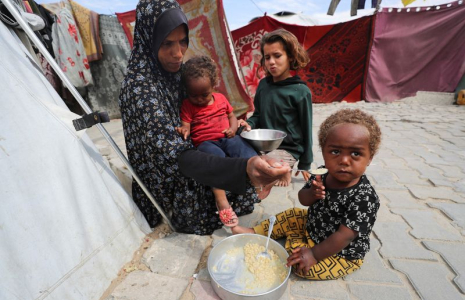 Une Palestinienne nourrit ses enfants devant la tente qui les abrite, à Gaza
