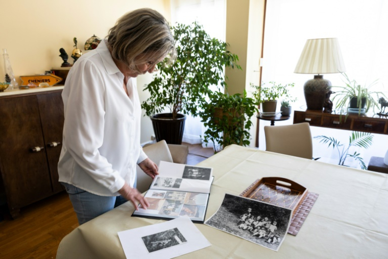 Claudine Spire regarde des photos de famille lors d'une interview à son domicile de Chaville, en région parisienne, le 9 avril 2025 ( AFP / Xavier GALIANA )