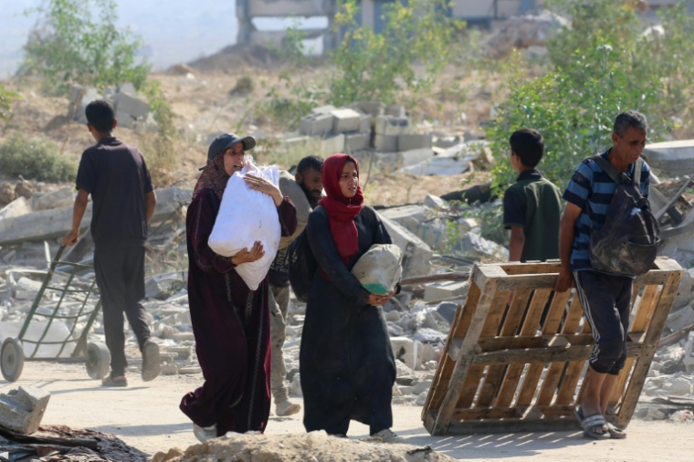 Des Palestiniens transportent de l'aide humanitaire après une distribution à Nousseirat, dans le centre de la bande de Gaza, le 26 septembre 2025 ( AFP / Eyad BABA )