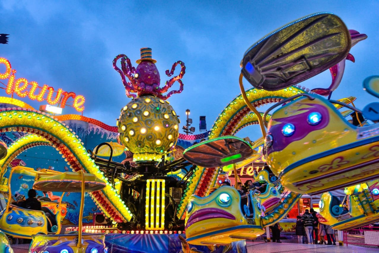 (Crédits photo : Adobe Stock - Manèges d'une fête foraine pour les familles à la tombée de la nuit)