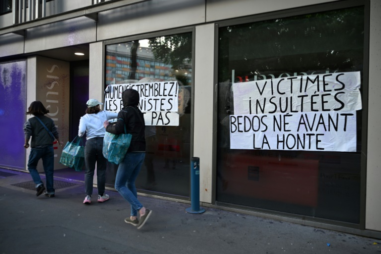 Des militantes féministes collent des affiches pour protester contre la parution du dernier livre de Nicolas Bedos, le 23 mai 2025 à Paris ( AFP / Leo VIGNAL )