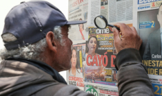 Un homme utilise une loupe pour lire les journaux sur la destitution de la présidente Dina Boluarte par les parlementaires péruviens, mettant fin à un mandat marqué par des manifestations, des enquêtes pour corruption et une criminalité croissante, à Lima, le 10 octobre 2025. ( AFP / CONNIE FRANCE )