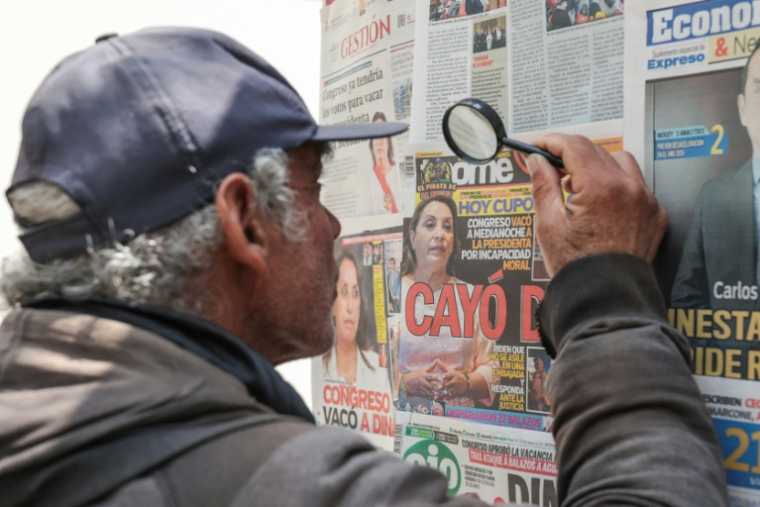 Un homme utilise une loupe pour lire les journaux sur la destitution de la présidente Dina Boluarte par les parlementaires péruviens, mettant fin à un mandat marqué par des manifestations, des enquêtes pour corruption et une criminalité croissante, à Lima, le 10 octobre 2025. ( AFP / CONNIE FRANCE )