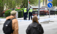 Des passants observent des policiers travaillant sur les lieux d'une fusillade meurtrière à Uppsala (Suède), le 30 avril 2025 ( TT NEWS AGENCY / Fredrik SANDBERG )