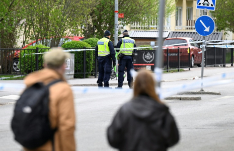 Des passants observent des policiers travaillant sur les lieux d'une fusillade meurtrière à Uppsala (Suède), le 30 avril 2025 ( TT NEWS AGENCY / Fredrik SANDBERG )