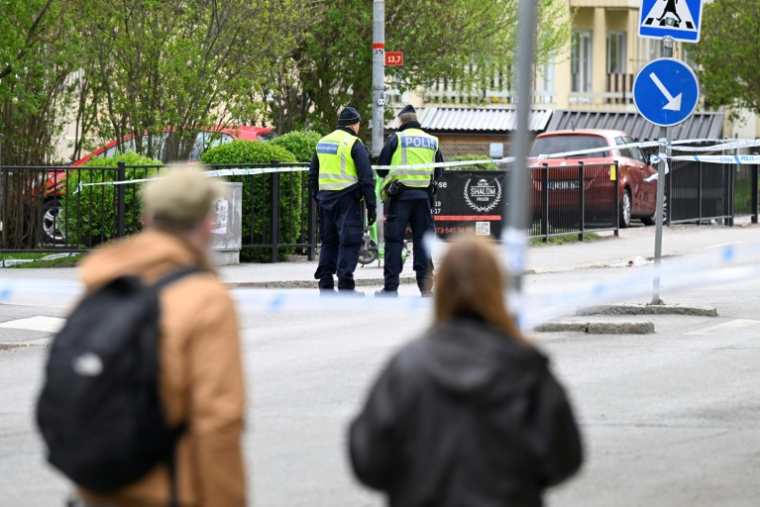 Des passants observent des policiers travaillant sur les lieux d'une fusillade meurtrière à Uppsala (Suède), le 30 avril 2025 ( TT NEWS AGENCY / Fredrik SANDBERG )