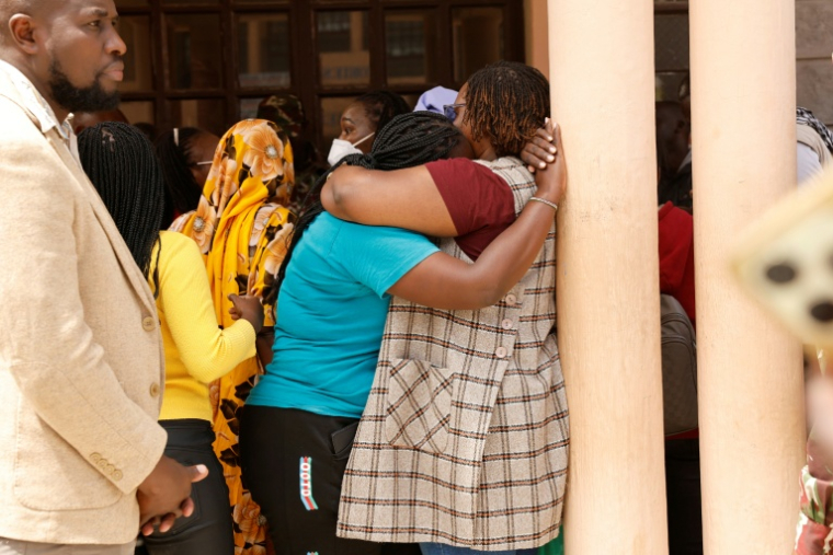 Deux proches d'élèves se réconfortent le 28 mai 2026 dans la cour de l'école de filles de Gilgil, au Kenya, où un dortoir a été ravagé durant la nuit par un incendie meurtrier ( AFP / SIMON MAINA )