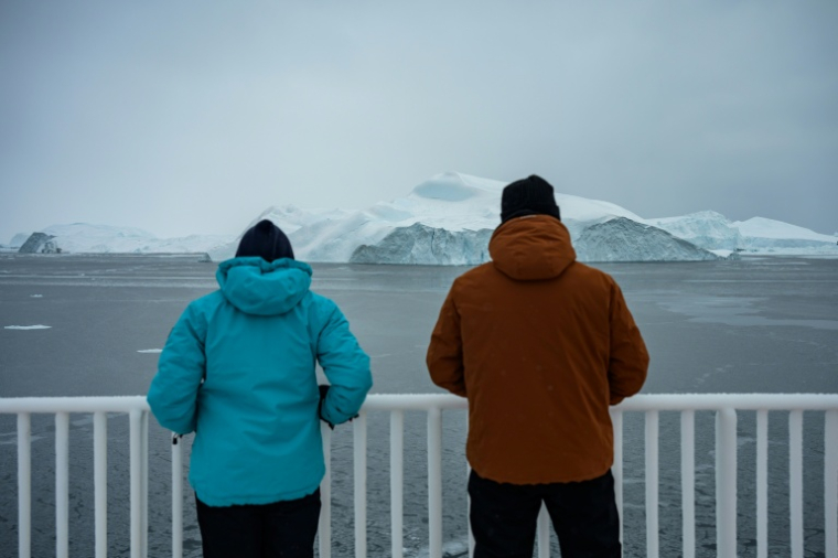Des touristes observent des icebergs dériver depuis le pont du ferry Sarfaq Ittuk dans la baie de Disko, près d'Ilulissat, au Groenland, le 15 mars 2026 ( AFP / Florent VERGNES )