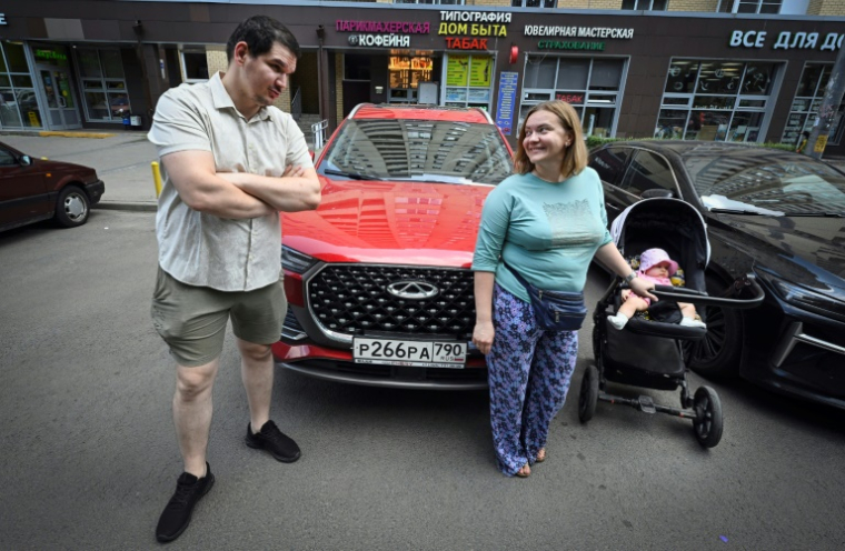 Sergueï Dioujikov, Maria Tiabout et leur bébé devant leur nouvelle voiture chinoise, le 17 juin 2025 à Mytichtchi, une ville de 300.000 habitants au nord-est de Moscou ( AFP / Alexander NEMENOV )