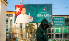 Cette photo prise le 20 décembre 2025 montre un homme passer devant un panneau de campagne de Khin Yi, de l'Union pour la solidarité et le développement, dans la région de Shan en Birmanie ( AFP / STR )