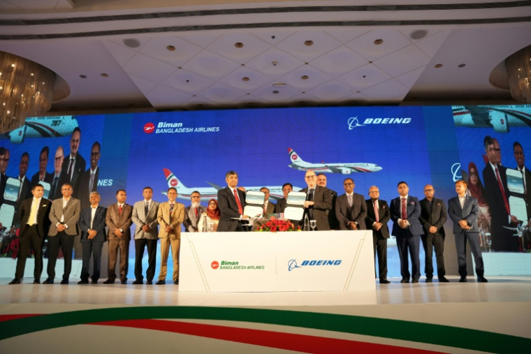 Photo diffusée par Biman Bangladesh Airlines montrant le PDG de compagnie aérienne, Kaizer Sohel Ahmed (g), et le vice-président de Boeing, Paul Righi (d), échangeant des documents après la signature d'un accord à Dacca, le 30 avril 2026 au Bangladesh ( Biman Bangladesh Airlines  / Handout )
