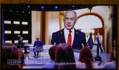 Cette photo prise sur un écran de TF1, montre le président français Emmanuel Macron, alors qu'une photo du Premier ministre israélien Benjamin Netanyahu s'affiche en arrière-plan, lors d'une émission dans les studios de télévision de Saint-Denis, le 13 mai 2025 ( AFP / Ludovic MARIN )